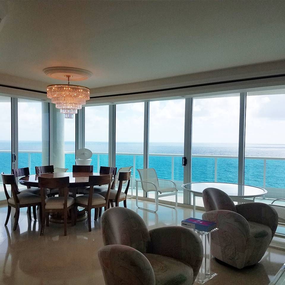 A dining room with a table and chairs and a view of the ocean