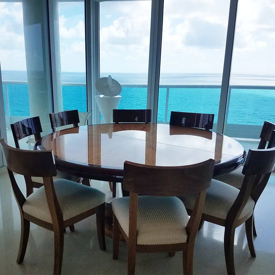 A round table and chairs in front of a balcony overlooking the ocean