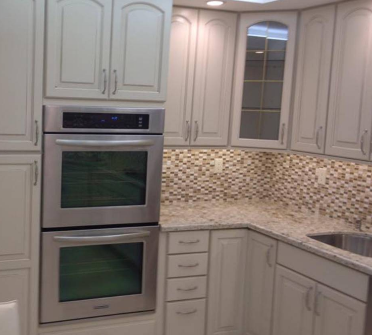 A kitchen with white cabinets and a stainless steel oven