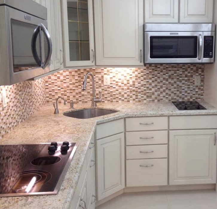 A kitchen with white cabinets and a stove top oven
