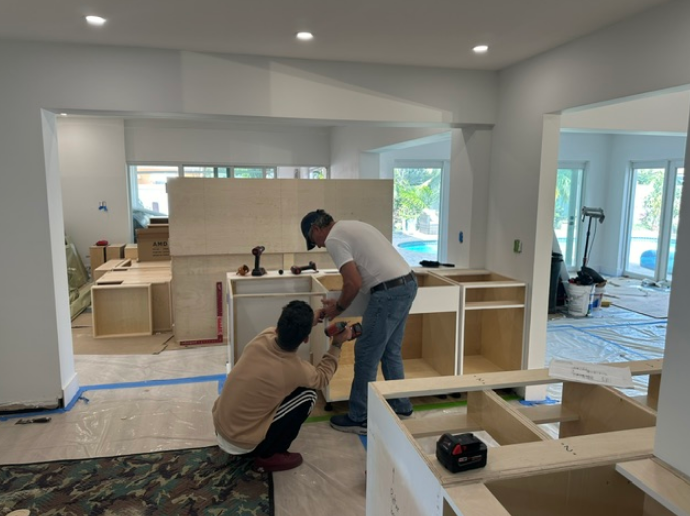 Two men are working on a kitchen in a house.