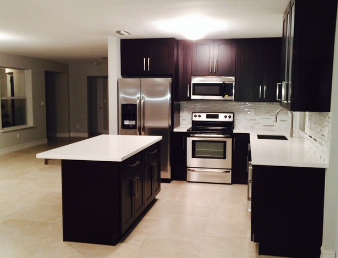 A kitchen with stainless steel appliances and black cabinets