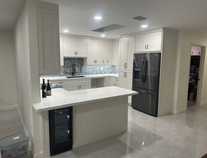 A kitchen with white cabinets and a stainless steel refrigerator.