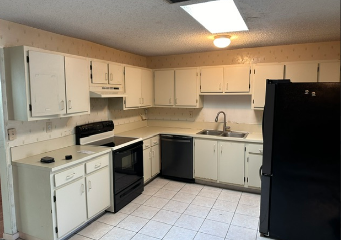 A kitchen with white cabinets and a black refrigerator