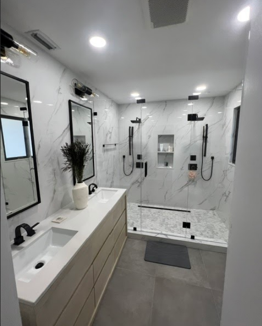 A bathroom with two sinks and a walk in shower