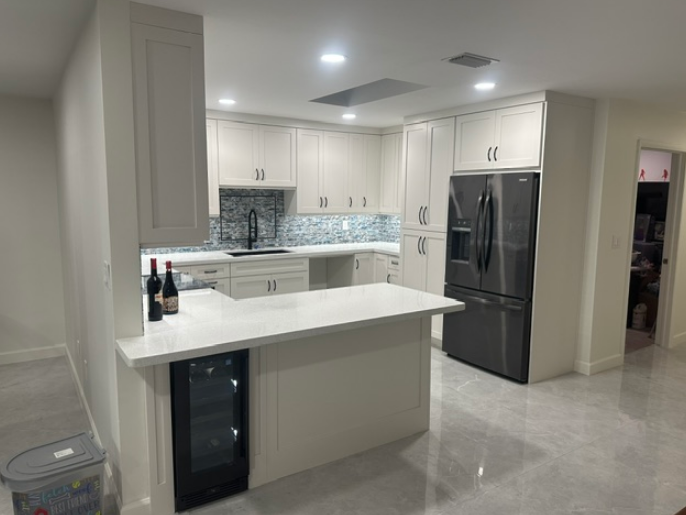 A kitchen with white cabinets and a stainless steel refrigerator.