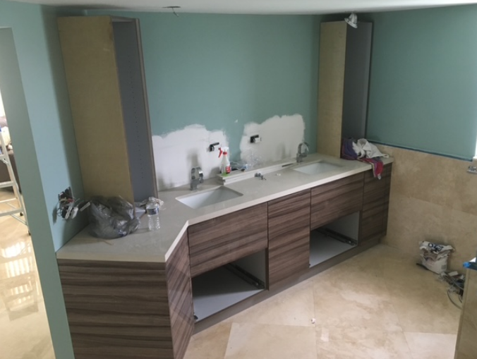 A bathroom under construction with two sinks and cabinets.