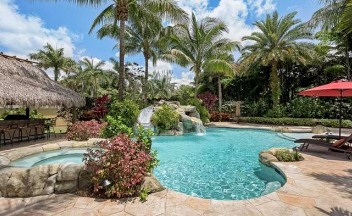 A large swimming pool surrounded by palm trees and umbrellas