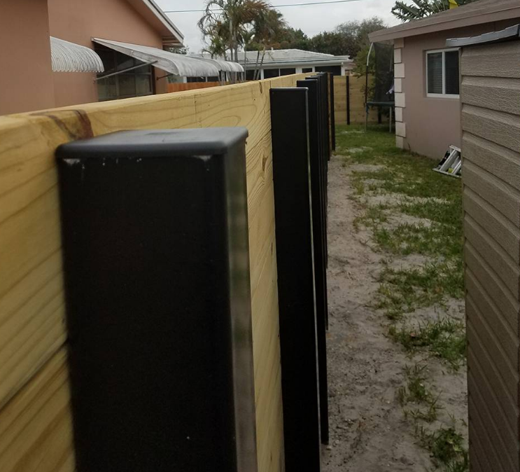 A wooden fence with black posts in front of a house