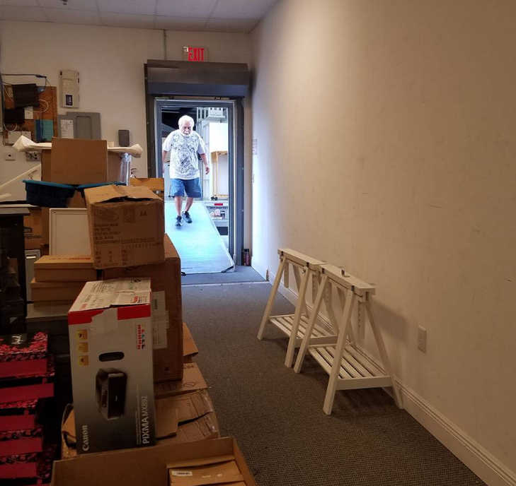 A man walking down a hallway with boxes and a sign that says exit