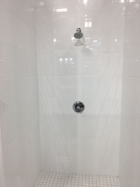 A white shower stall with two shower heads and a tiled floor.