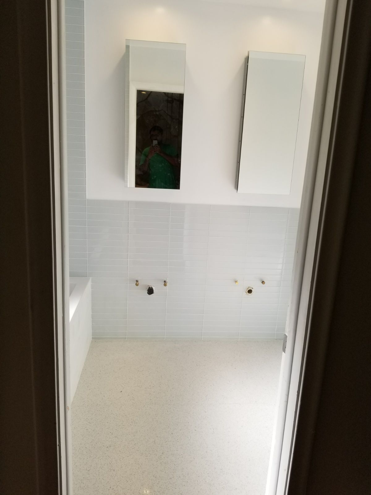 A bathroom with white tiles and a mirror on the wall