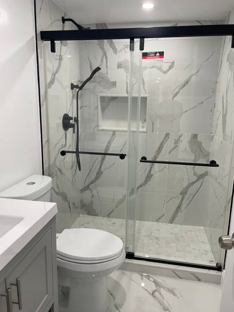 A bathroom with a toilet , sink and shower.