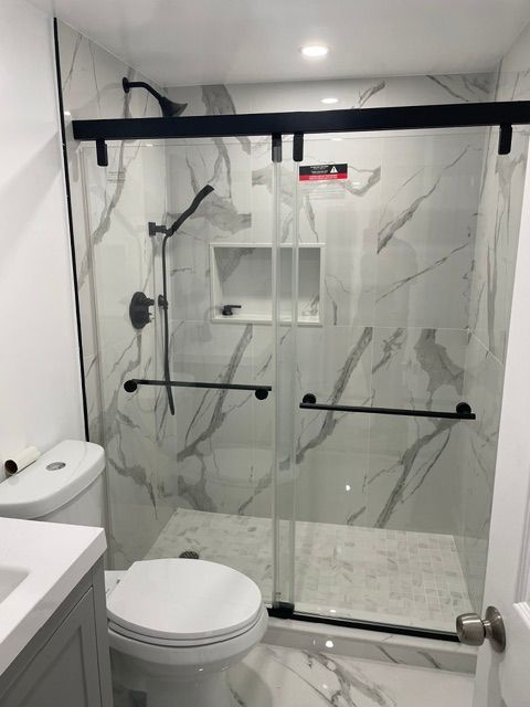 A bathroom with a toilet and a shower with sliding glass doors