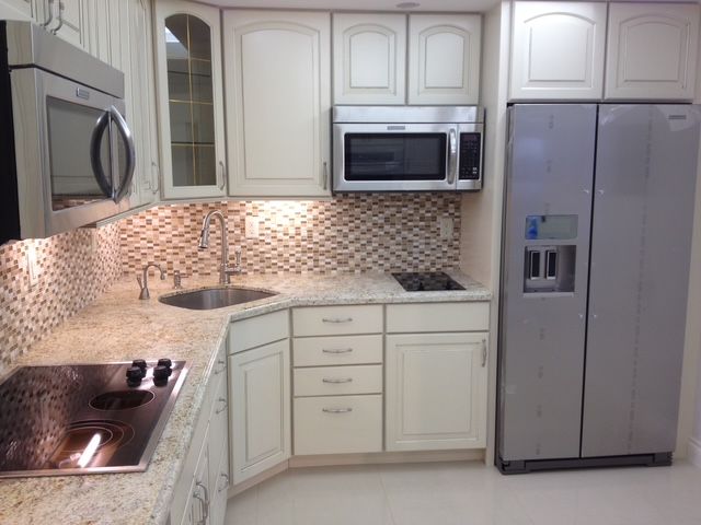 A kitchen with white cabinets and a silver refrigerator