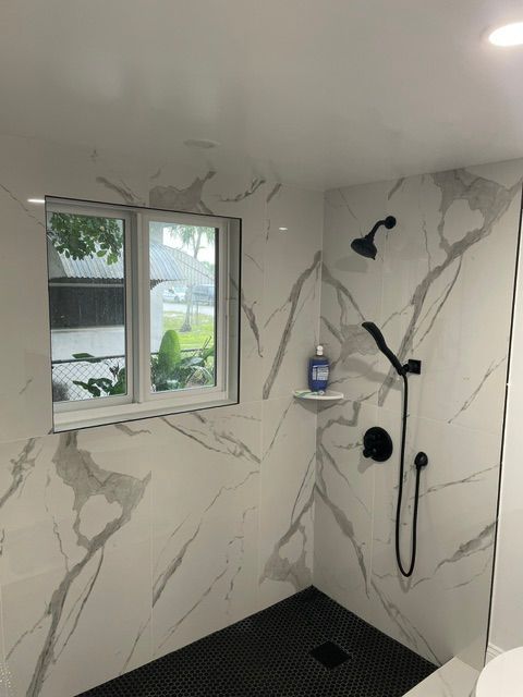 A bathroom with a walk in shower and a window