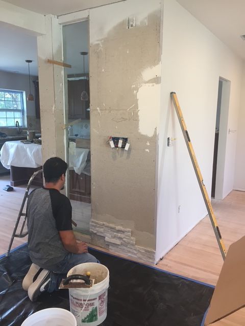 A man is kneeling down with a bucket of paint in front of him