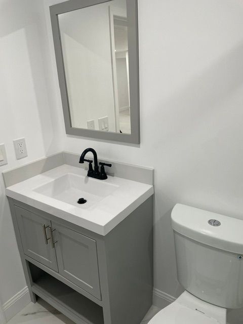A bathroom with a sink , toilet and mirror.