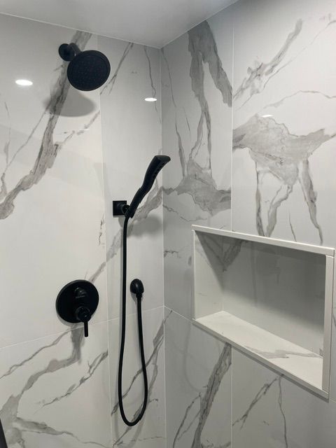 A shower with marble tiles and a black shower head