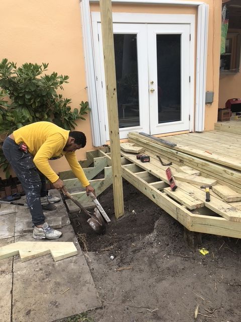 A man in a yellow shirt is working on a wooden deck