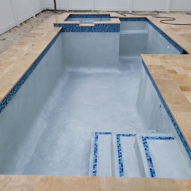 An empty swimming pool with blue tiles and stairs
