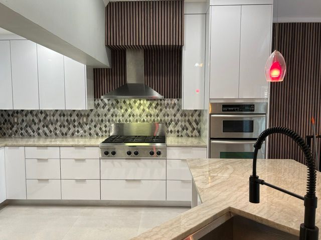 A kitchen with white cabinets , stainless steel appliances and a sink.