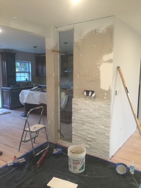 A bucket of paint sits on the floor in a room under construction
