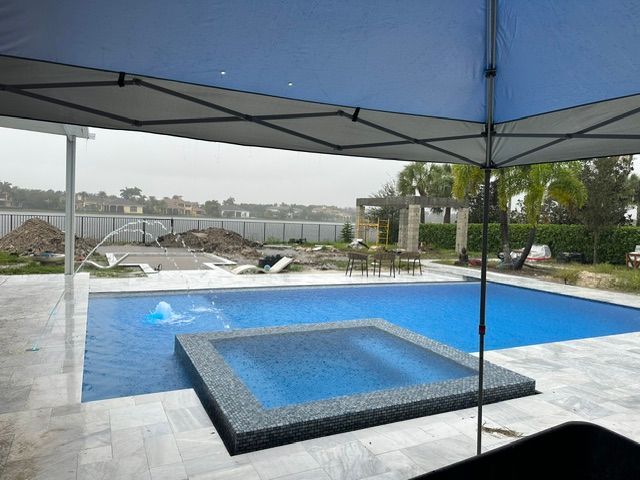 A large swimming pool with a hot tub under an umbrella.