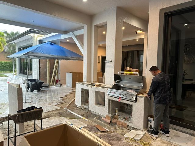A man is working on a grill in a backyard.