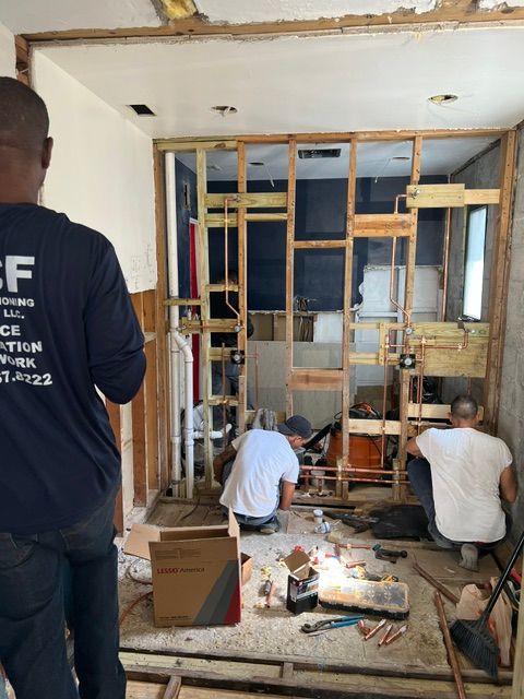 Construction workers in a bathroom. They're working on the framing and plumbing.