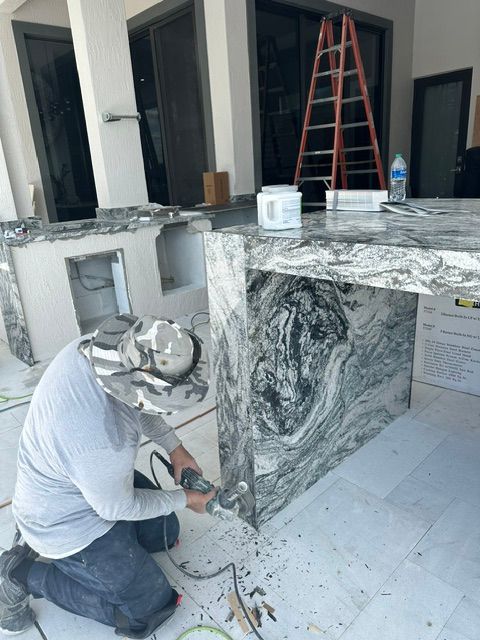 A man is kneeling on the floor working on a counter top