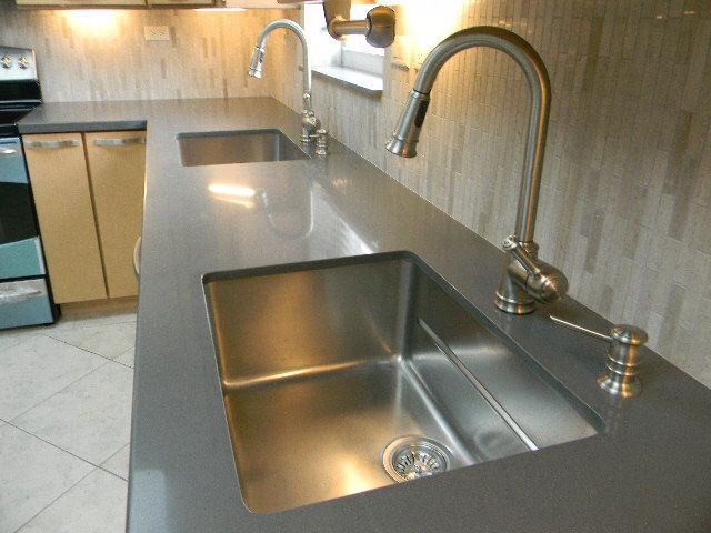 A kitchen with two stainless steel sinks and two faucets