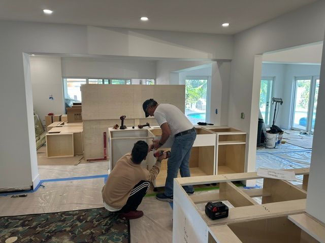 Two men are working on a kitchen in a house.