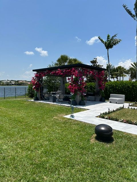 A gazebo with pink flowers in front of a body of water