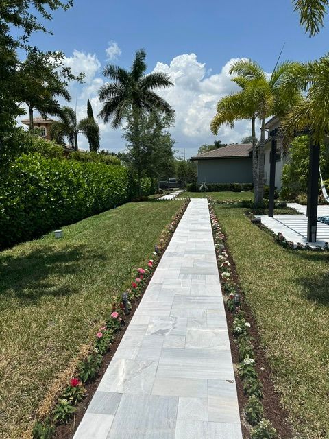 A walkway leading to a house with palm trees on the side