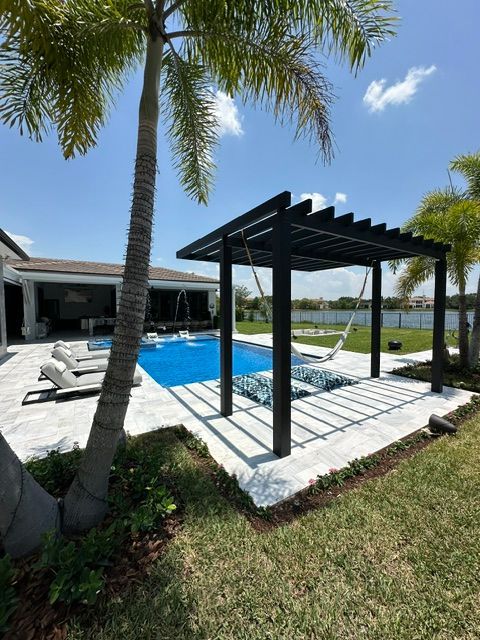 A large swimming pool with a pergola in front of it