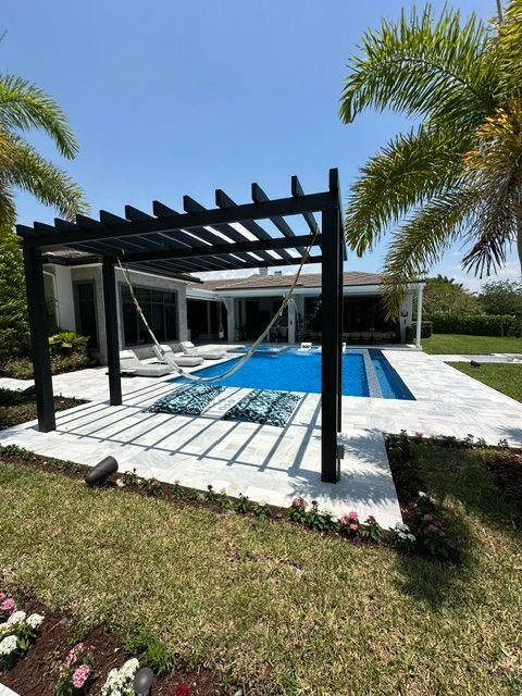 A house with a swimming pool and a pergola in front of it