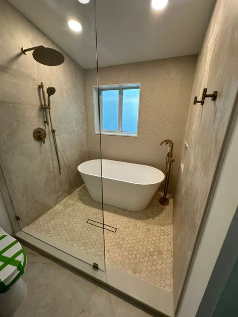 A bathroom with a bathtub , shower , toilet and window.