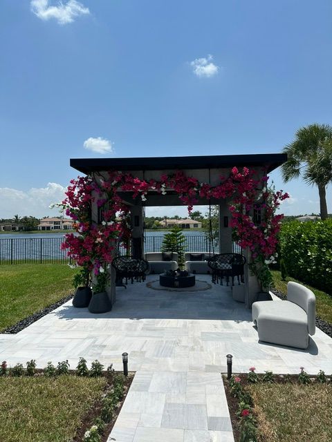 A gazebo with pink flowers in front of a lake