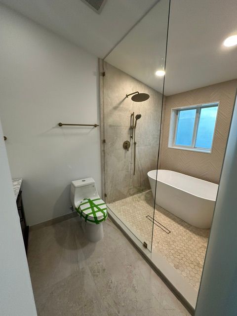 A bathroom with a toilet , tub , shower and window.