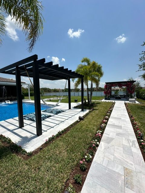 A swimming pool with a pergola and a walkway leading to it