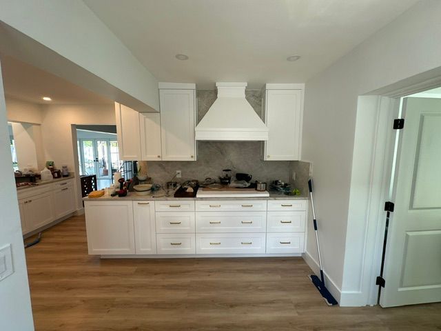 A kitchen with white cabinets and wooden floors