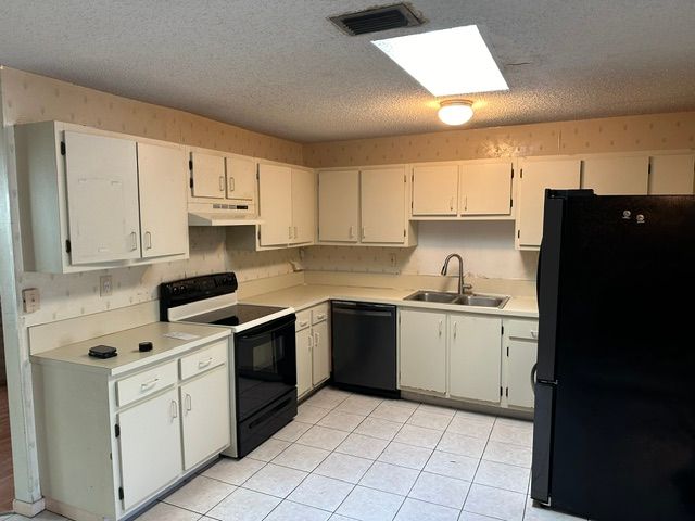 Kitchen with white cabinets, black appliances, and tiled floor.