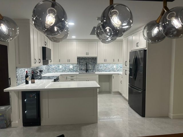 A kitchen with white cabinets and a black refrigerator