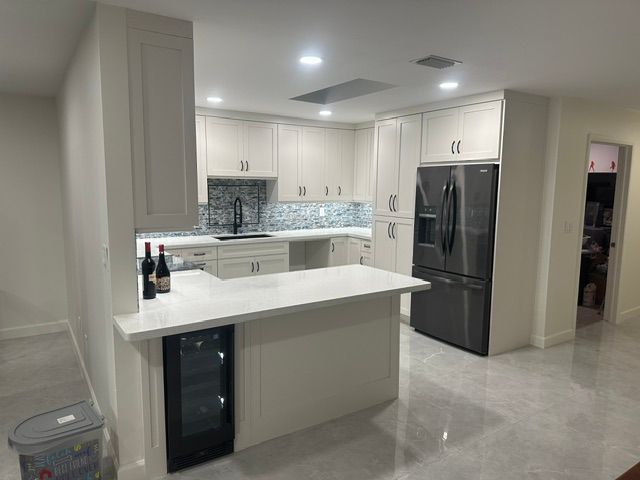 A kitchen with white cabinets and a stainless steel refrigerator.