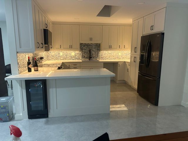 A kitchen with white cabinets and a black refrigerator