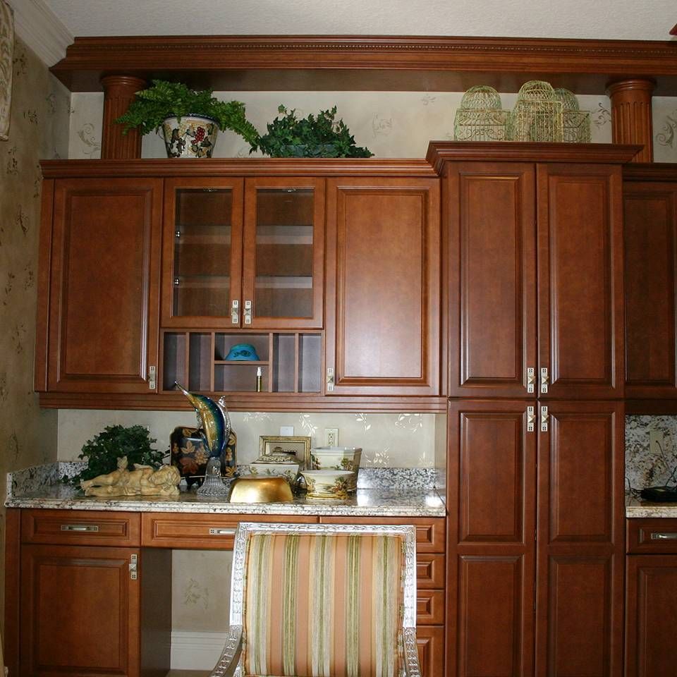 A kitchen with lots of wooden cabinets and a chair