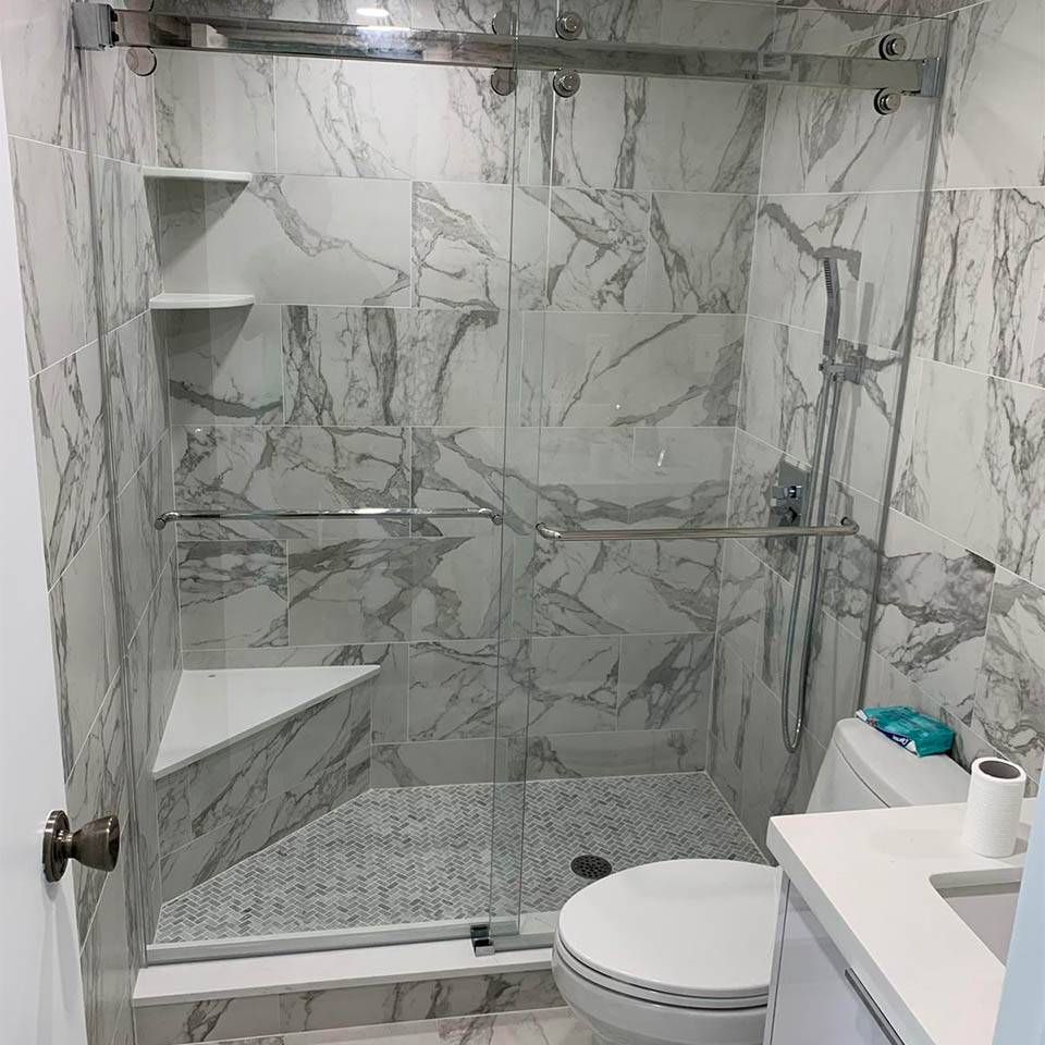 A bathroom with marble tiles and a sliding glass shower door.