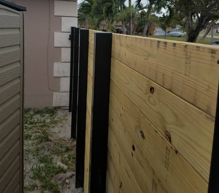 A wooden fence with black posts in front of a house