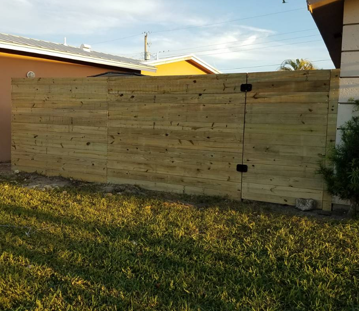 A wooden fence is in the backyard of a house.